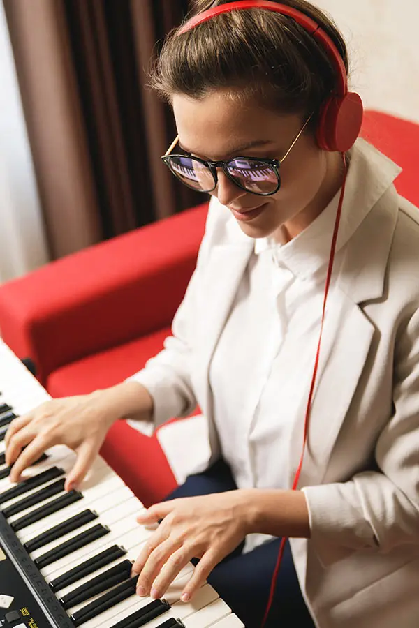 Woman in red headphones playing an electronic keyboard