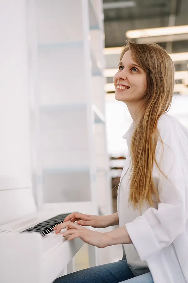 Woman smiling while playing a white piano