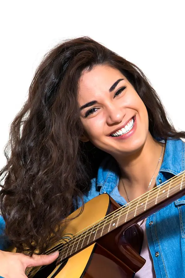 Smiling woman holding an acoustic guitar