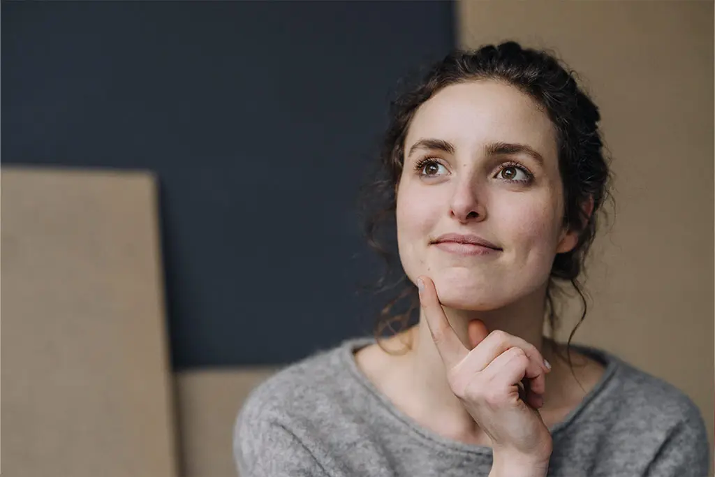 Woman looking thoughtful with her hand on her chin
