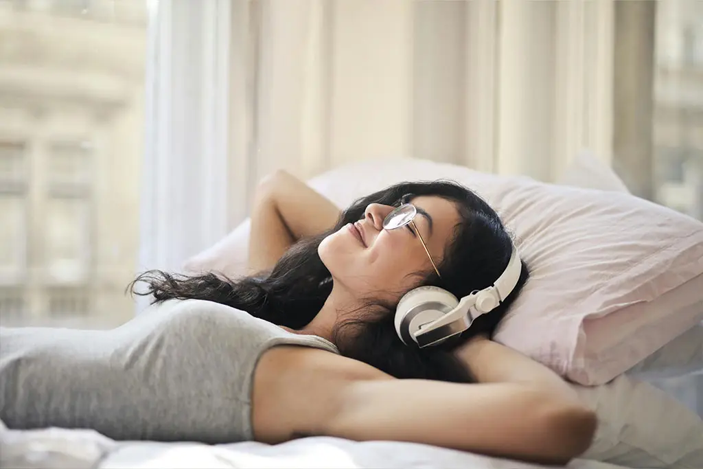 Woman relaxing in bed wearing headphones