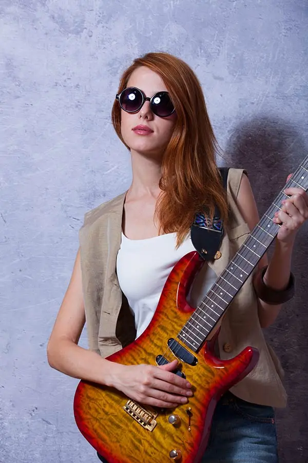 Woman wearing sunglasses holding an electric guitar