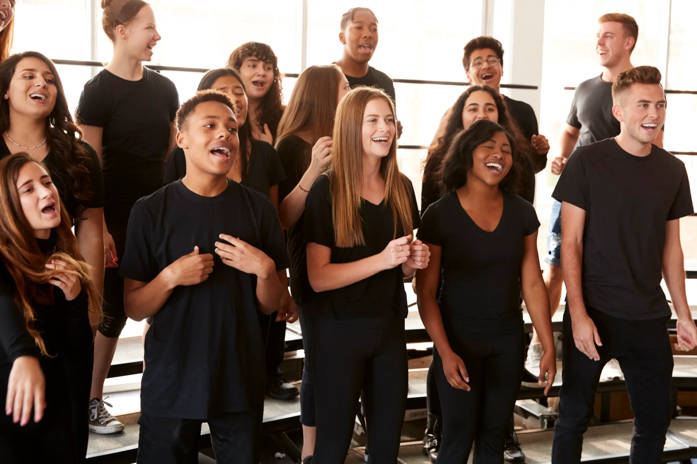 Group of young singers in black T-shirts singing together.