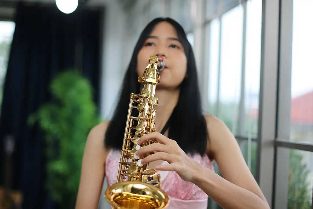 Young woman playing an alto saxophone indoors
