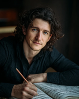A man writing on sheet music with a pencil