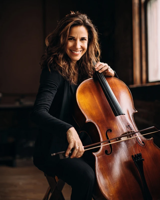 A smiling woman seated with her cello and bow