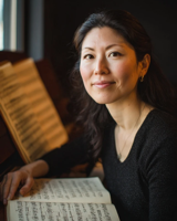 A smiling woman with an open book of sheet music